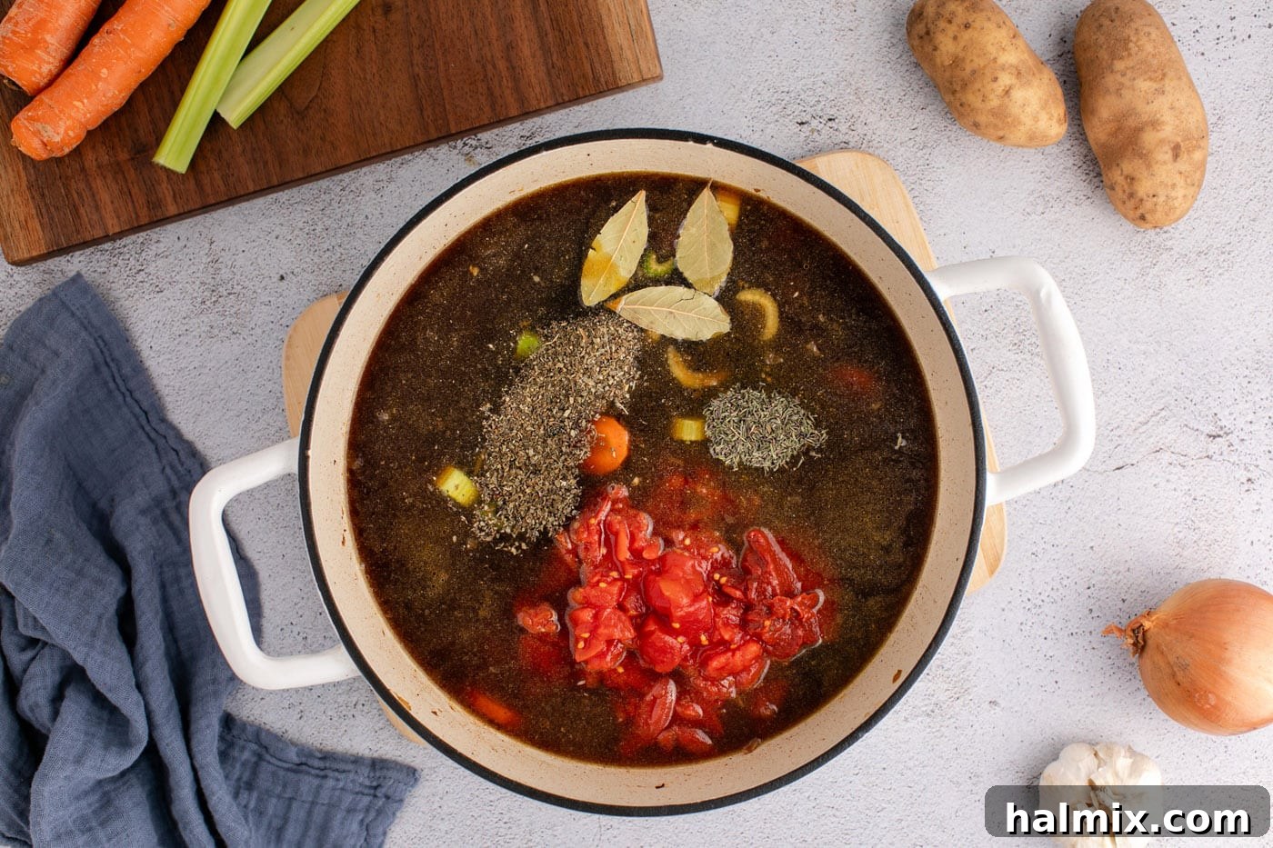 Beef broth, diced tomatoes, and herbs added to the soup base in the Dutch oven.