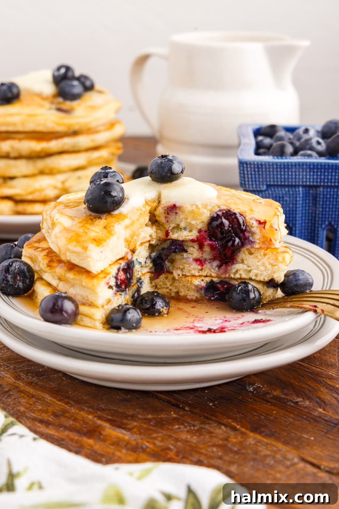 Stack of warm Blueberry Pancakes on a plate with a bite removed