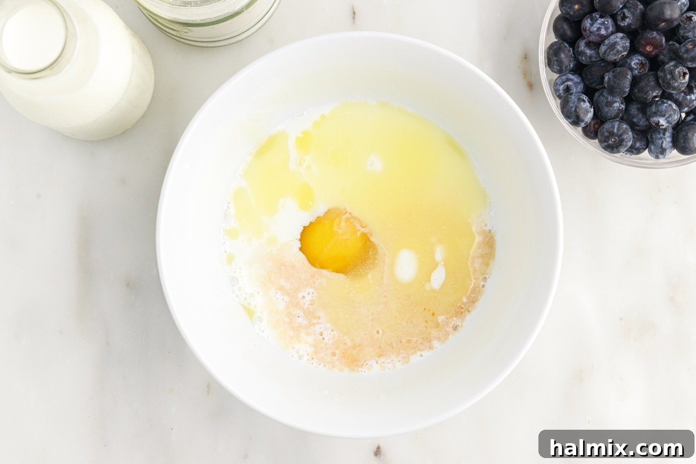 adding eggs, butter, vanilla, and buttermilk to dry ingredients for pancake batter