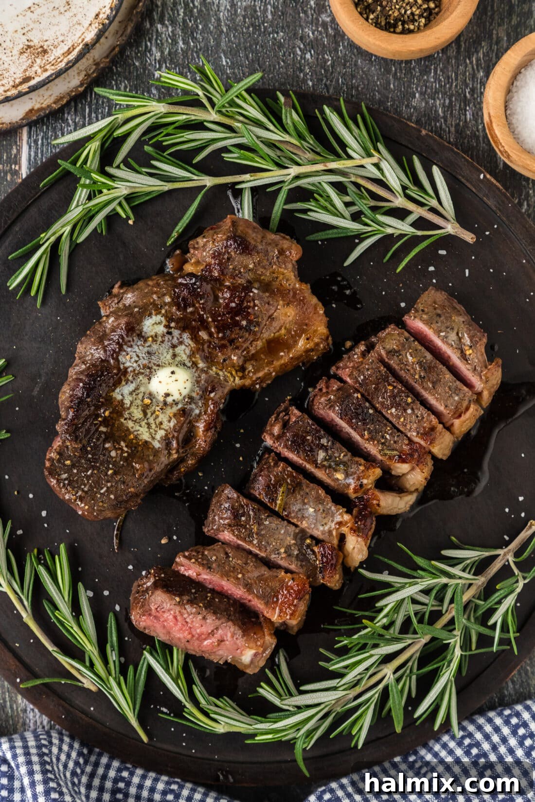 Two Sous Vide Steaks on a platter with one cut into slices, revealing a perfect medium-rare doneness