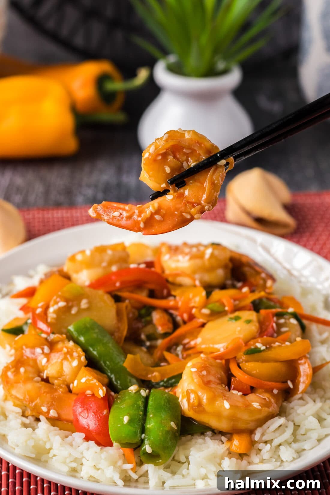 Sweet Chili Shrimp Stir-Fry 13 Chopsticks holding up a piece of shrimp over a plate of Shrimp Stir Fry