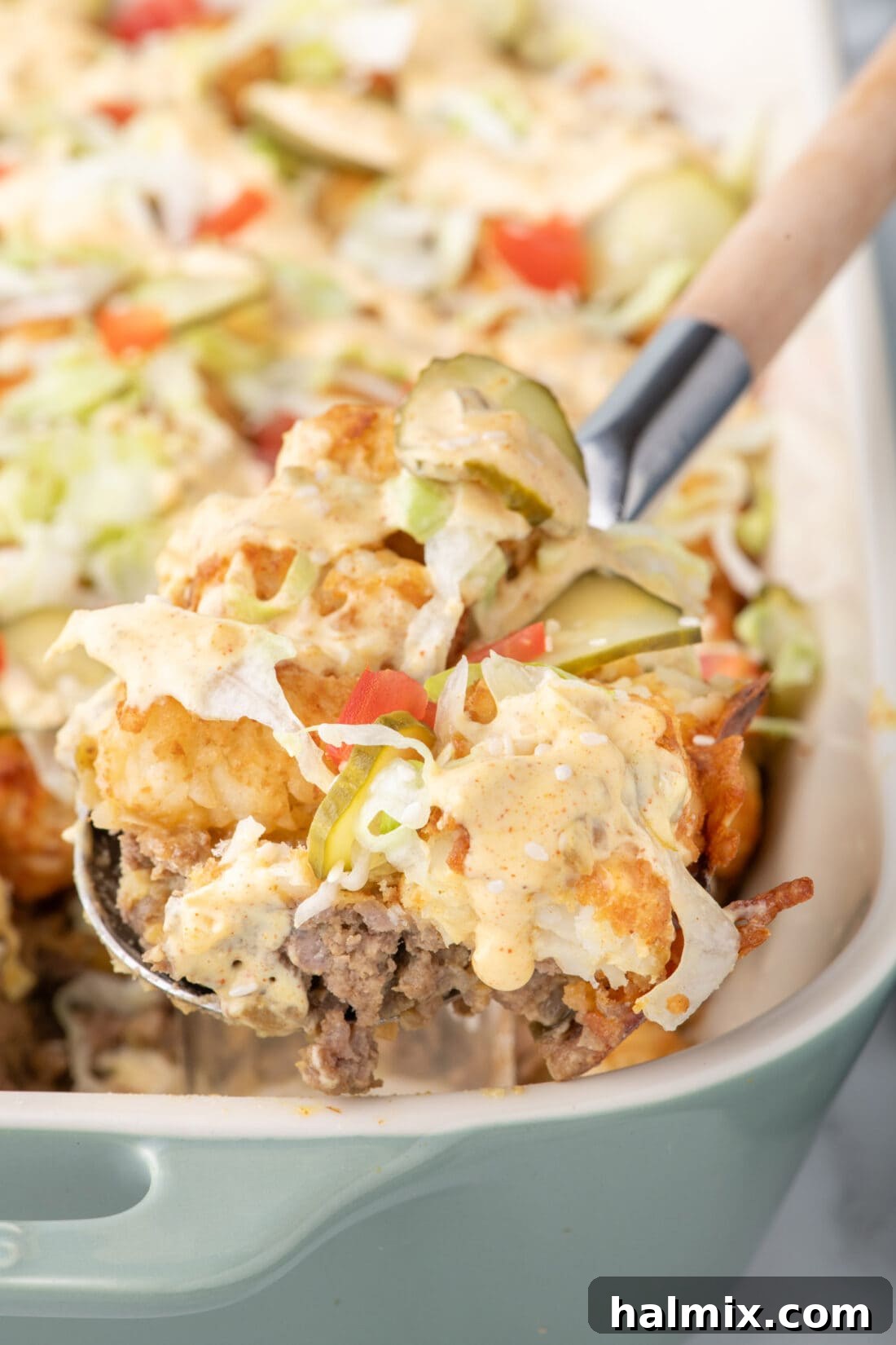 A large spoonful of Big Mac Casserole being lifted out of a casserole dish, highlighting the delicious layers.