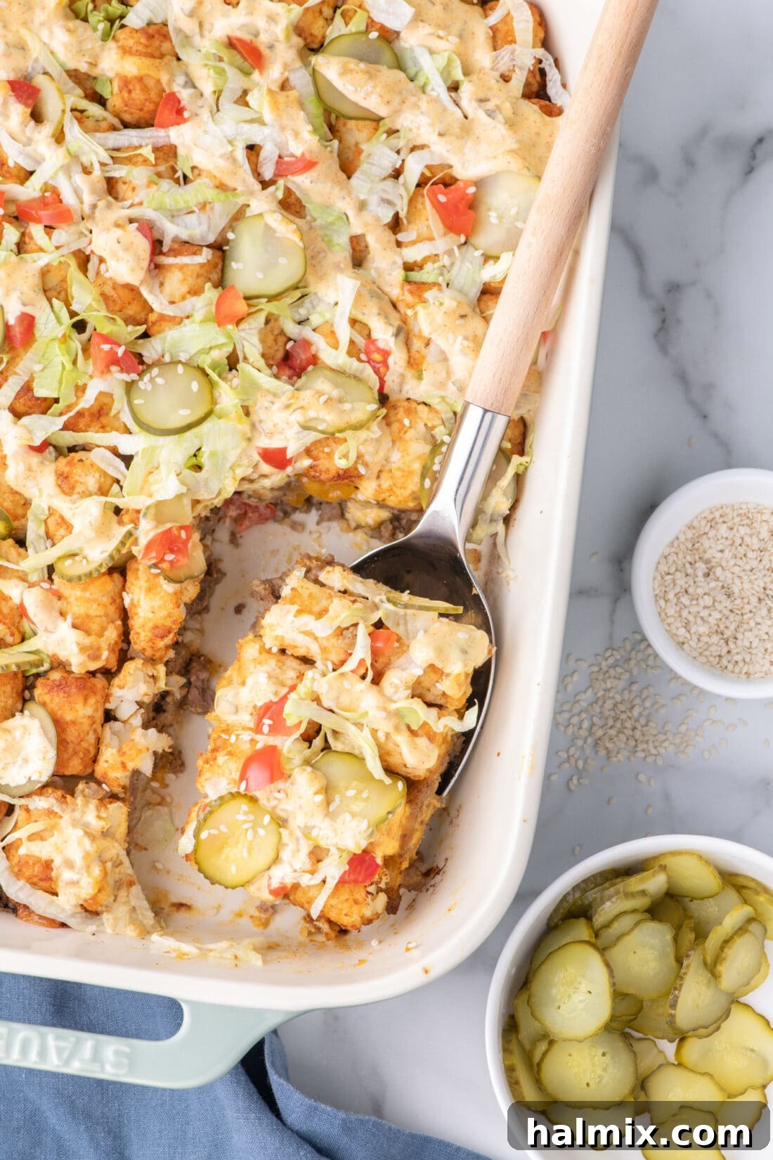 A spoonful of delicious Big Mac Casserole resting in a casserole dish, showing the layers of beef, cheese, and tater tots.