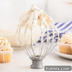 Brown Butter Cream Cheese Frosting 14 Brown Butter Frosting on a whisk attachment for mixer with cupcakes behind it