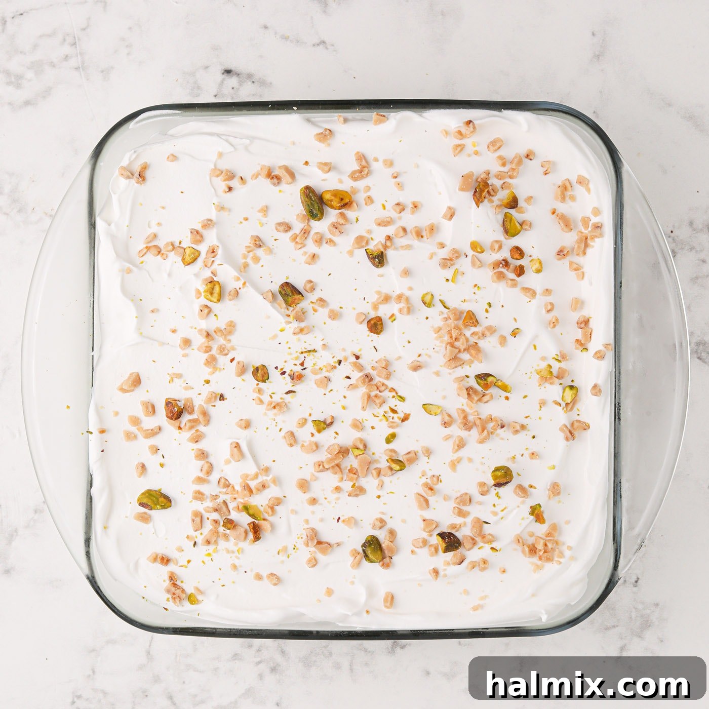 Crushed pistachios sprinkled generously on top of the whipped topping and pistachio ice cream cake.