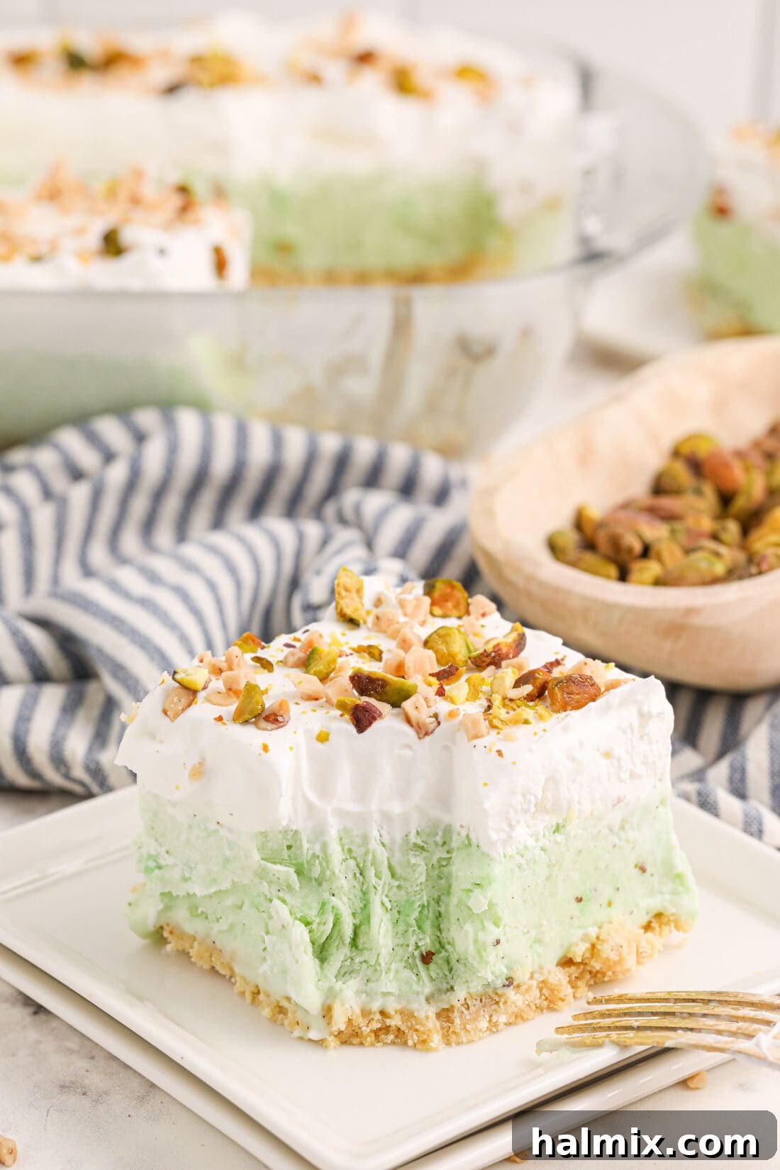 A pristine slice of Pistachio Ice Cream Cake on a white plate, with a small bite removed, highlighting its beautiful layers and tempting texture.