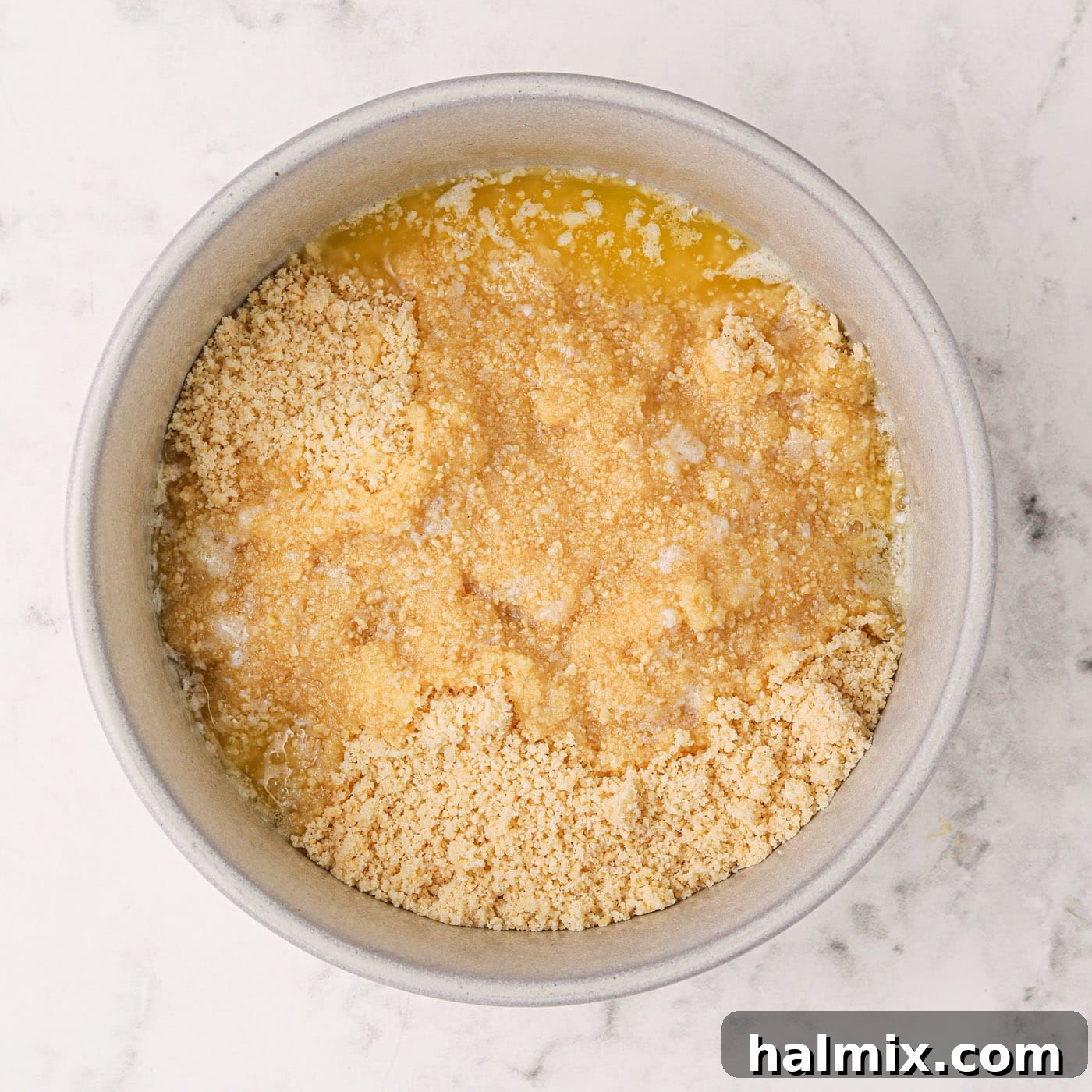 Crushed golden Oreos mixed with melted butter in a bowl, ready to be pressed into the crust.