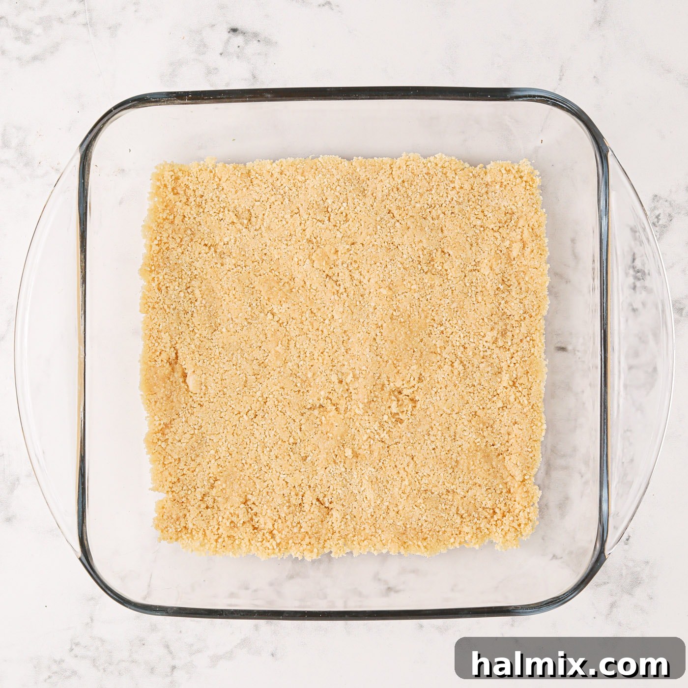 The golden Oreo cookie crust firmly pressed into the bottom of a square baking pan.