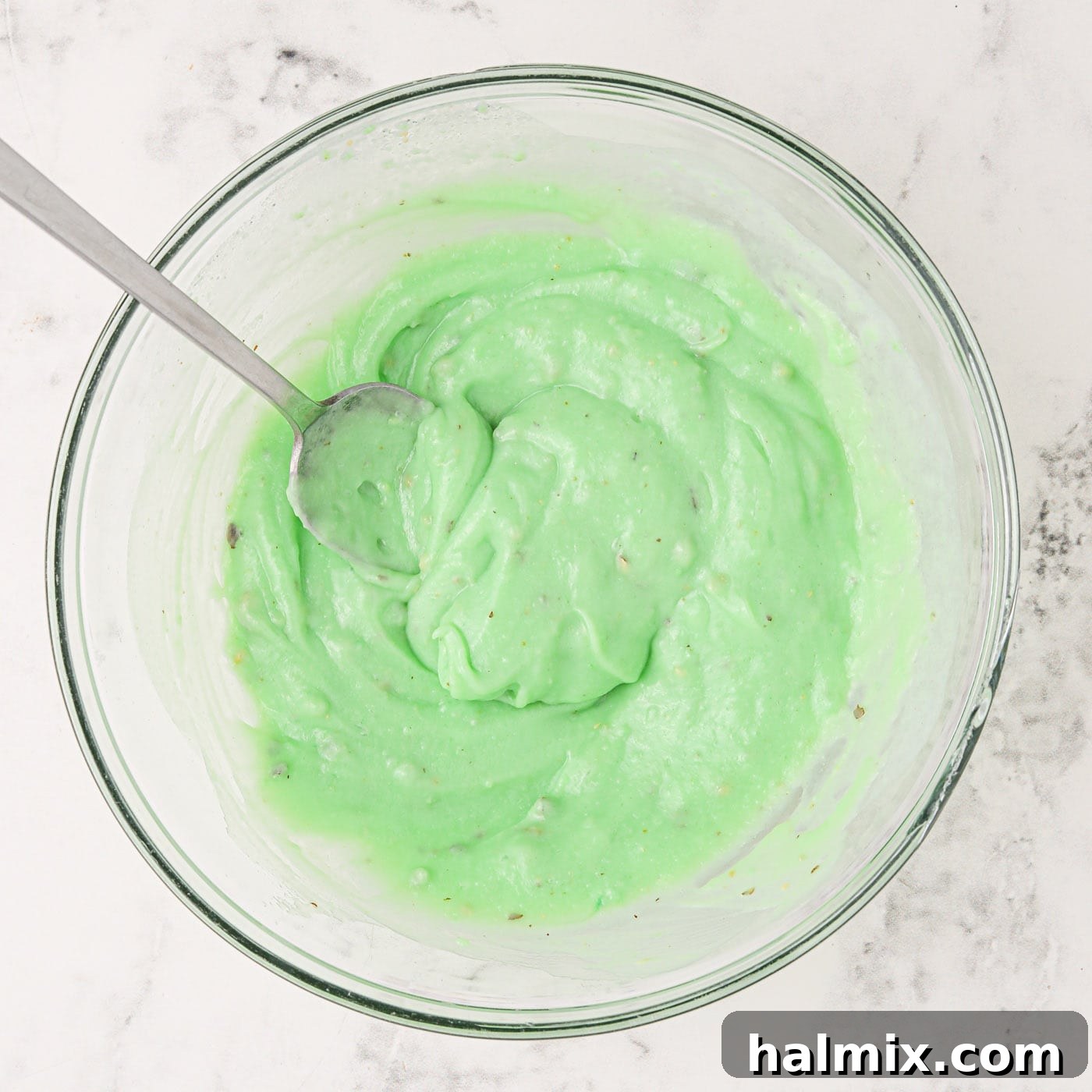 Instant pistachio pudding mix being whisked with cold milk in a mixing bowl.