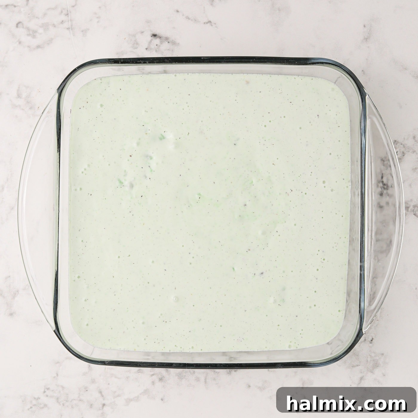 The pistachio ice cream mixture poured over the cookie crust in the baking dish, ready for freezing.