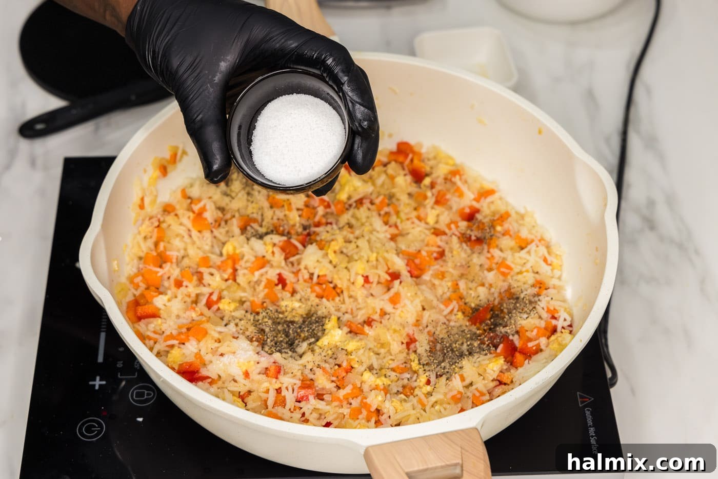 Salt and sugar being sprinkled into a skillet of fried rice, ready for mixing.