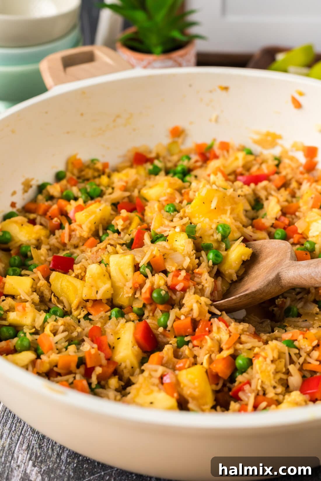 Close-up photo of Pineapple Fried Rice in a skillet with a spoon, showing the texture and ingredients.