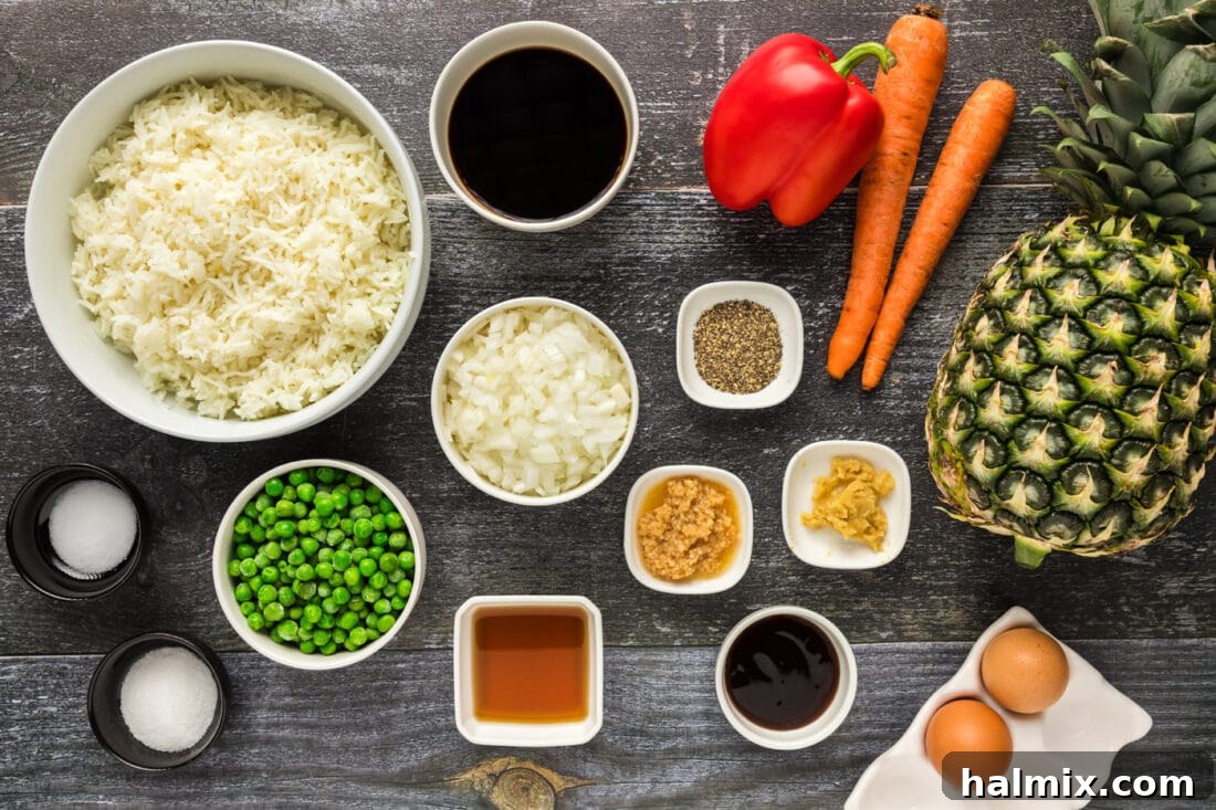 Arrangement of fresh ingredients for Pineapple Fried Rice, including pineapple, rice, vegetables, and sauces.