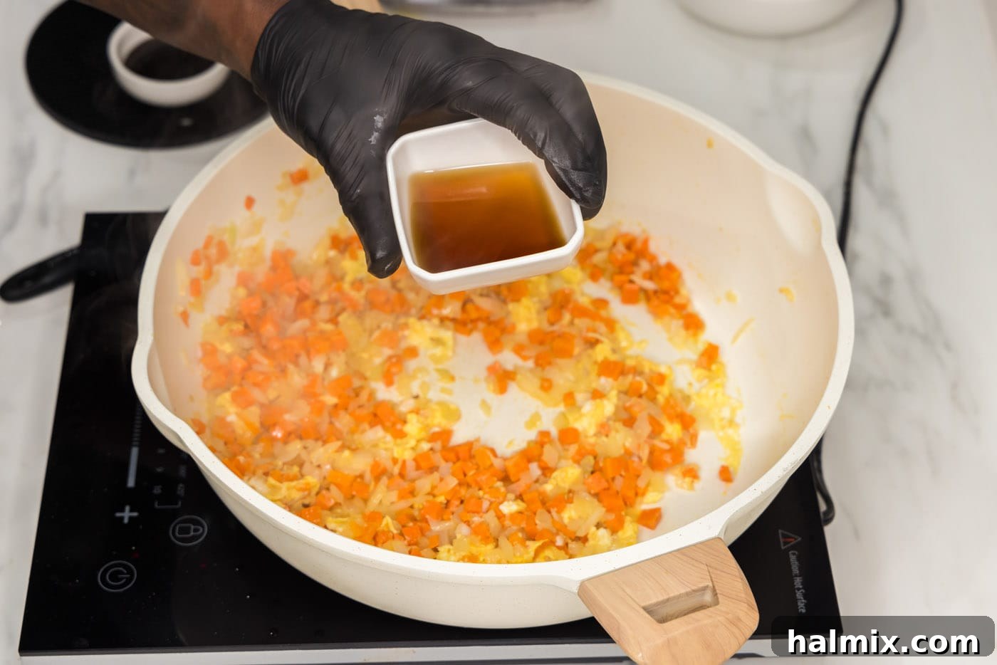 Fish sauce being poured into a skillet with scrambled eggs and vegetables.