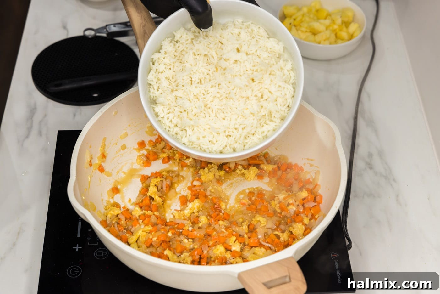 Cooked rice added to a pan with stir-fried vegetables and scrambled egg.