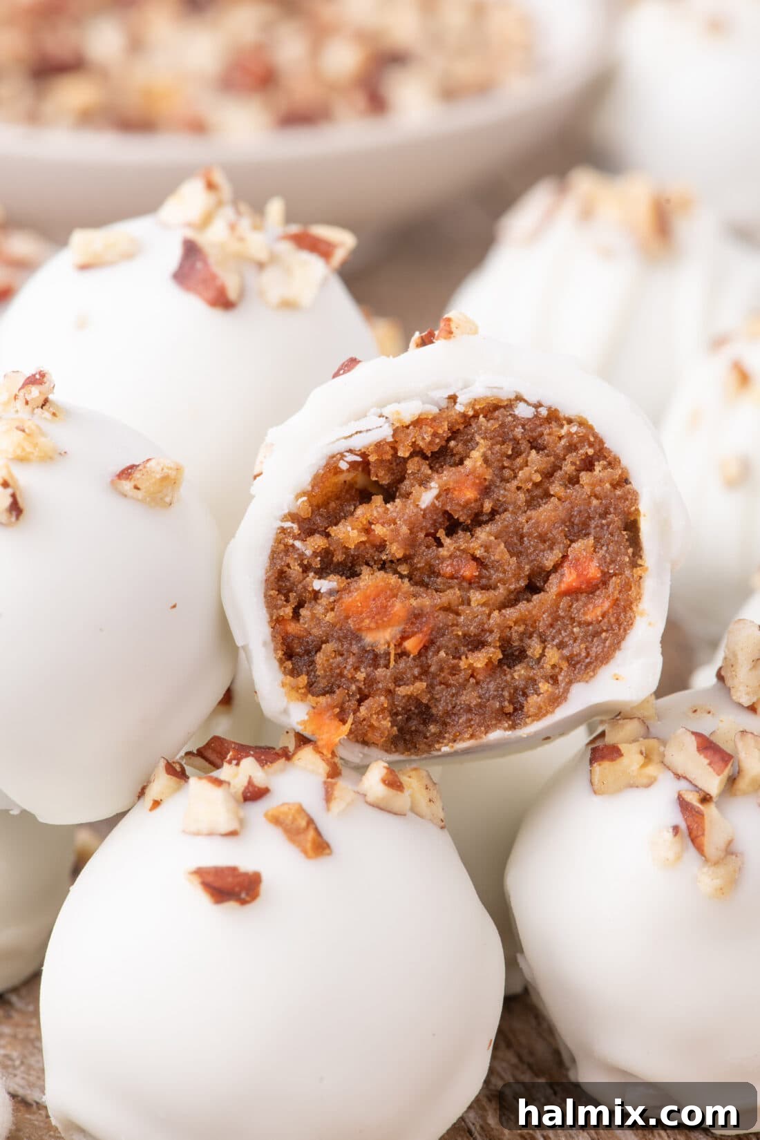Close up photo of a Carrot Cake Truffle cut in half resting on more Carrot Cake Truffles, showcasing its moist interior