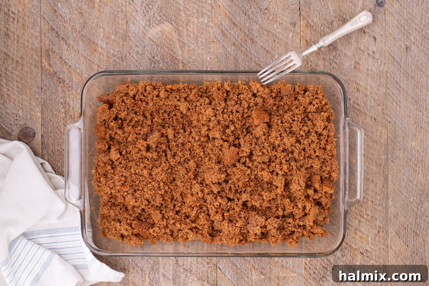 Warm carrot cake crumbled into small pieces within the baking pan, ready for frosting