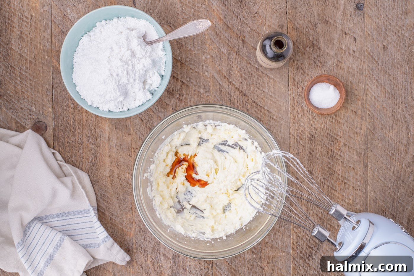 Vanilla extract being mixed into softened butter and cream cheese for frosting
