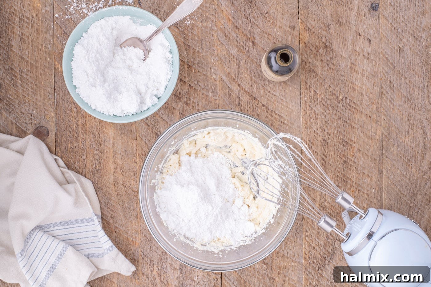 Slowly adding powdered sugar to the cream cheese and butter mixture for frosting