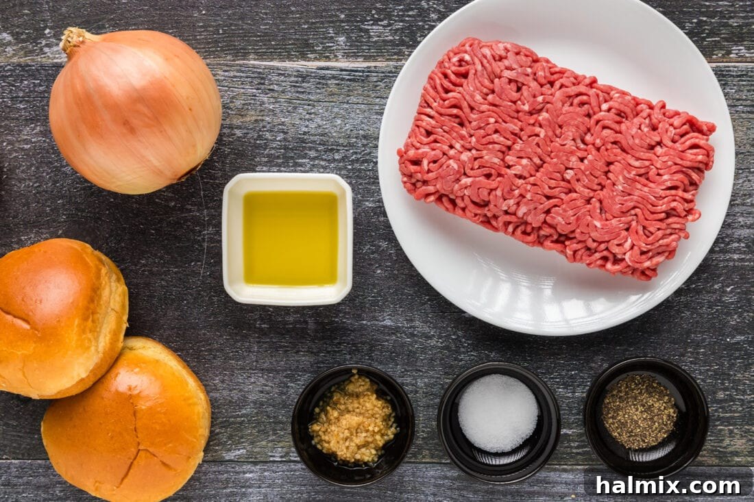 Fresh ingredients for making air fryer burgers, including ground beef, garlic, onion, salt, pepper, and olive oil, neatly arranged on a wooden board.