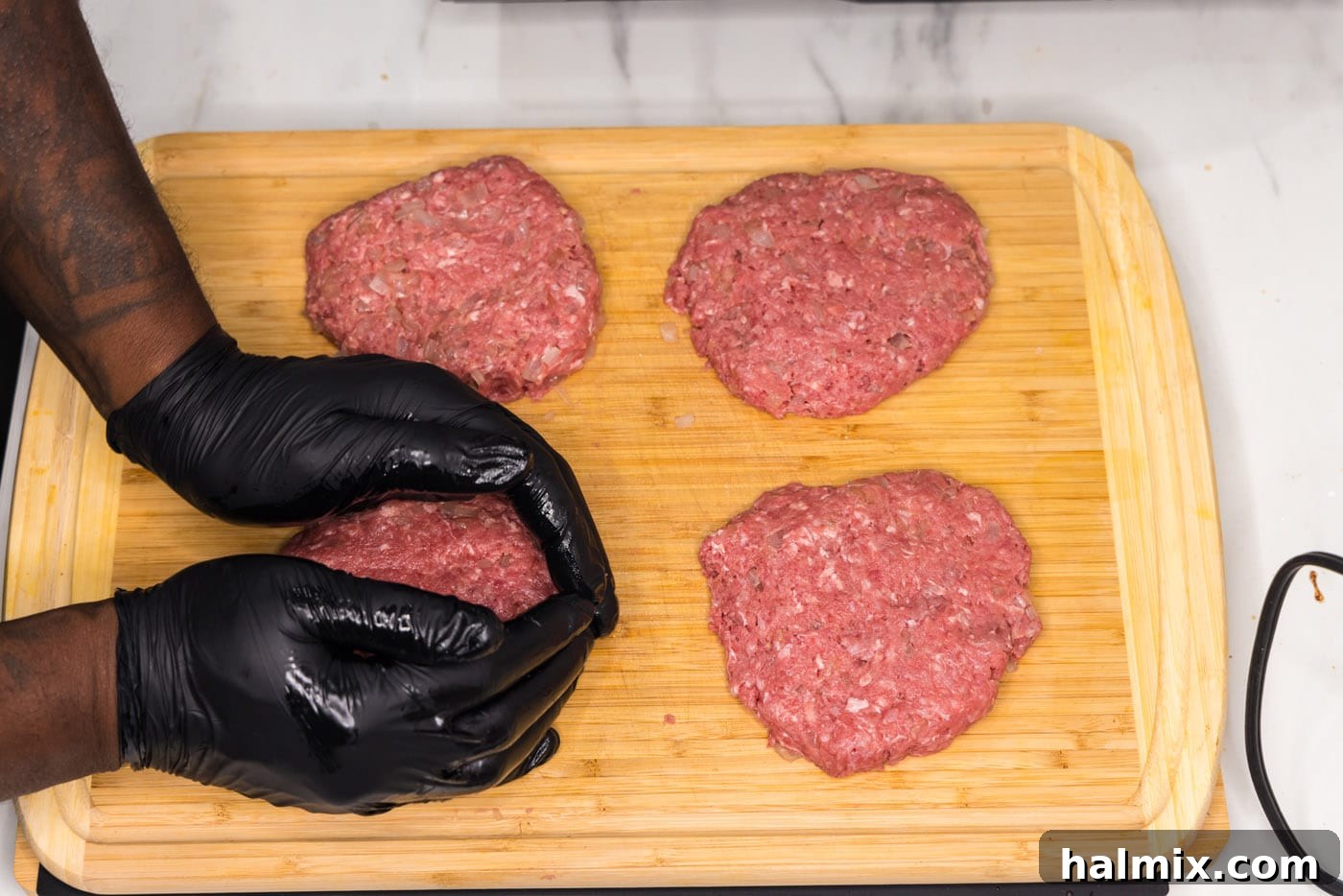 Hands carefully shaping portions of ground beef into uniform burger patties.