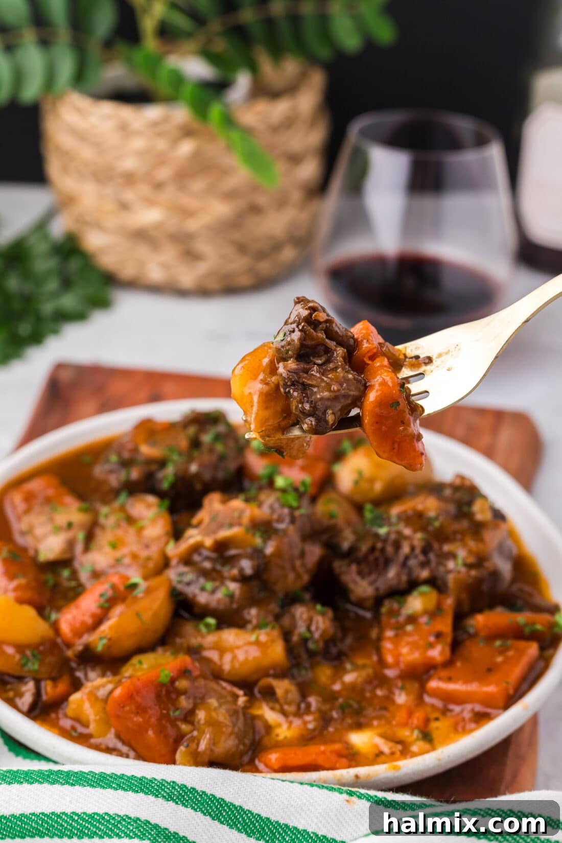 Instant Pot Oxtail on a fork held above a plate of Instant Pot Oxtail
