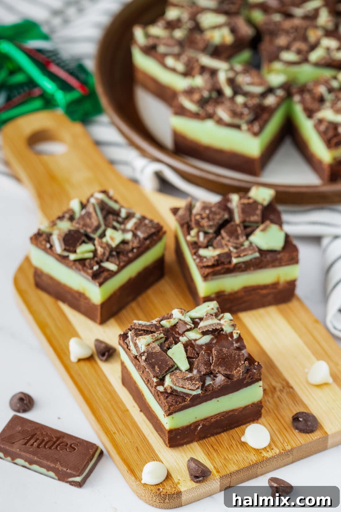 Three squares of Andes Mint Fudge on a wooden board