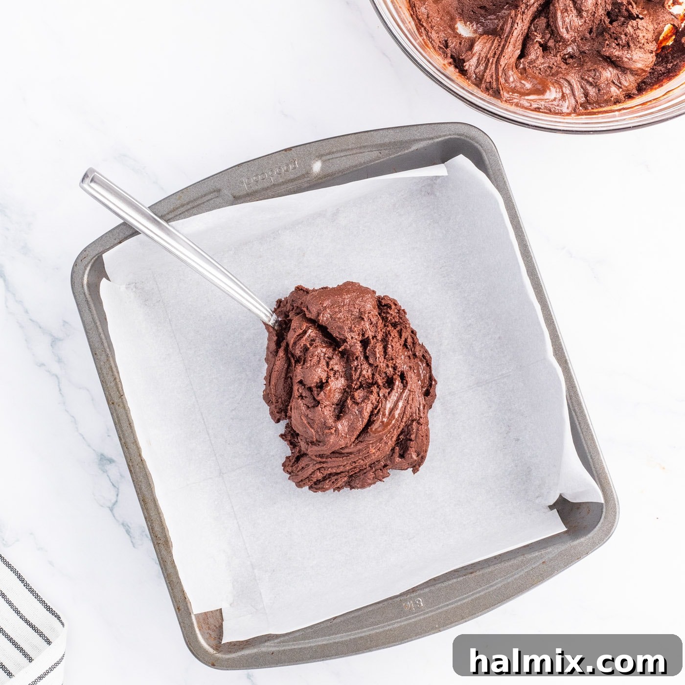 spreading chocolate fudge mixture in a baking pan
