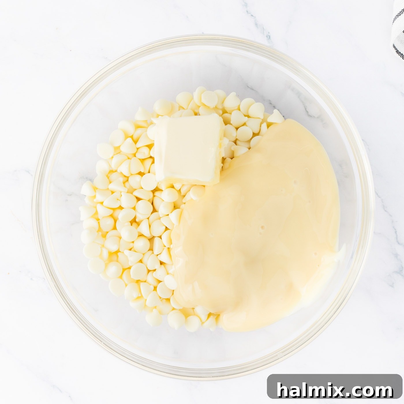 white chocolate chips in a bowl with sweetened condensed milk and butter