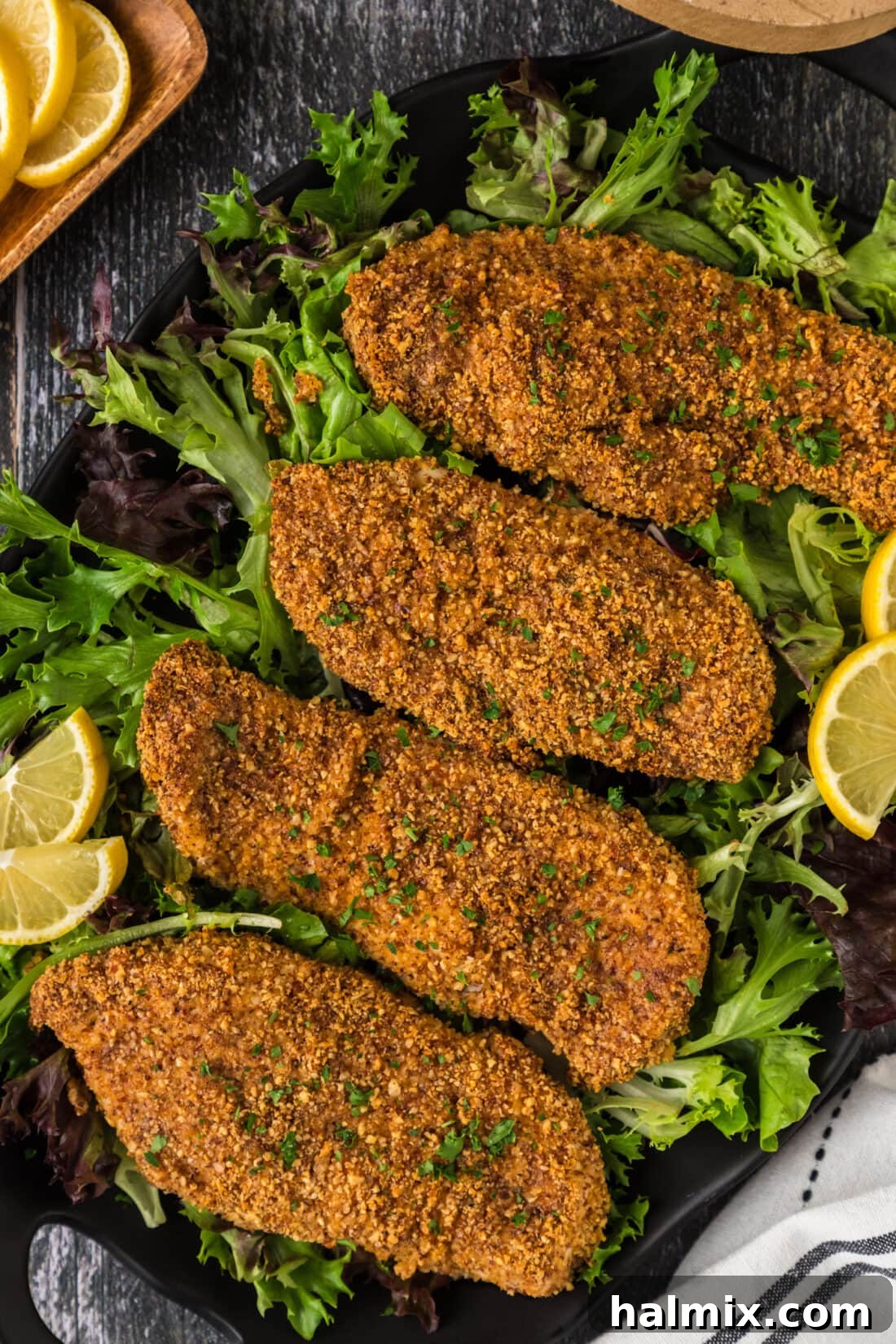 Four Almond Crusted Chicken breasts perfectly golden brown on a platter, ready to be served.