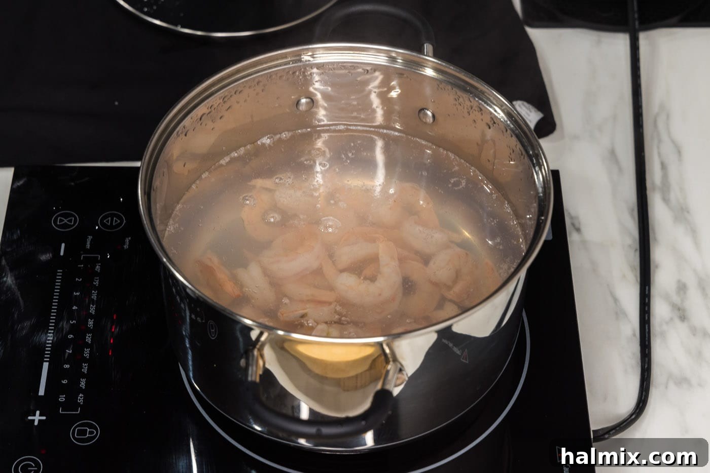 boiling shrimp in a stock pot. The shrimp are pink and curled, indicating they are perfectly cooked in the water.