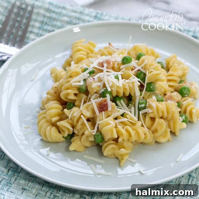 A plate featuring a serving of Rotini with Peas and Cheese, showcasing the golden pasta and bright green peas.