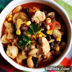 A close up overhead photo of a bowl of chicken chili with black beans and corn.