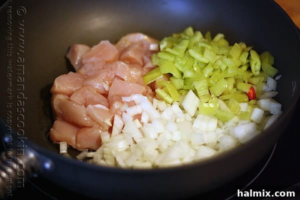 Hearty Chicken Chili with Black Beans and Sweet Corn 6 A close-up shot of cubed chicken, vibrant banana peppers, and diced onions sizzling in a skillet.