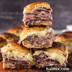 Close up photo of a stack of Roast Beef Sliders, showcasing their golden buns and appealing layers