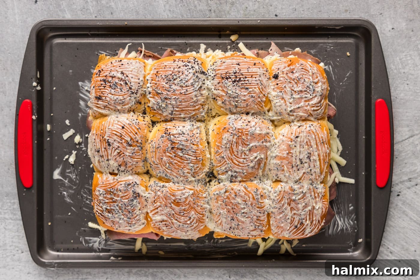 Garlic butter roast beef sliders, freshly baked and golden brown with poppy seeds, ready to be sliced