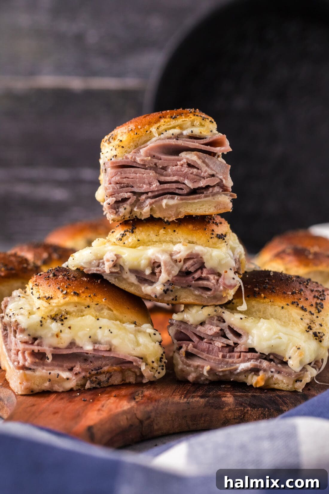 A beautifully arranged stack of Roast Beef Sliders, golden brown and garnished with poppy seeds