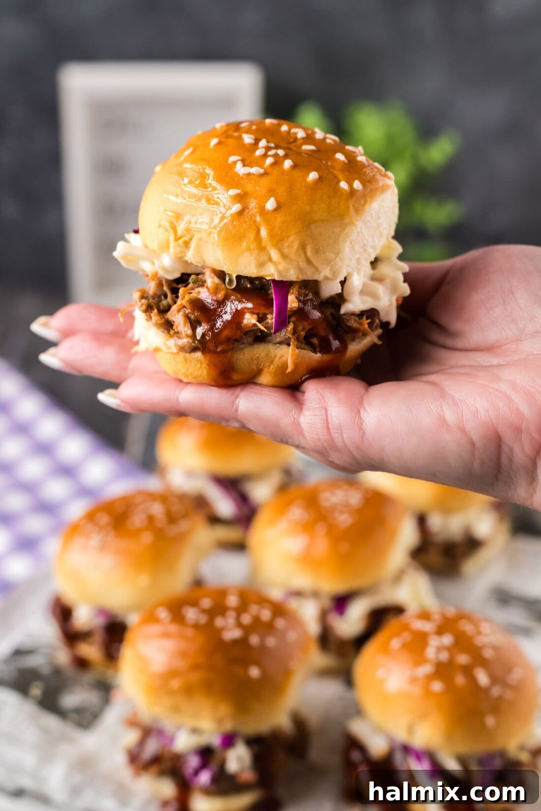 Pulled Pork Mini Buns 2 Hand holding up a Pulled Pork Slider over more Pulled Pork Sliders