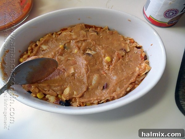 Layering the chicken mixture over tortillas and sauce in the tostada casserole.