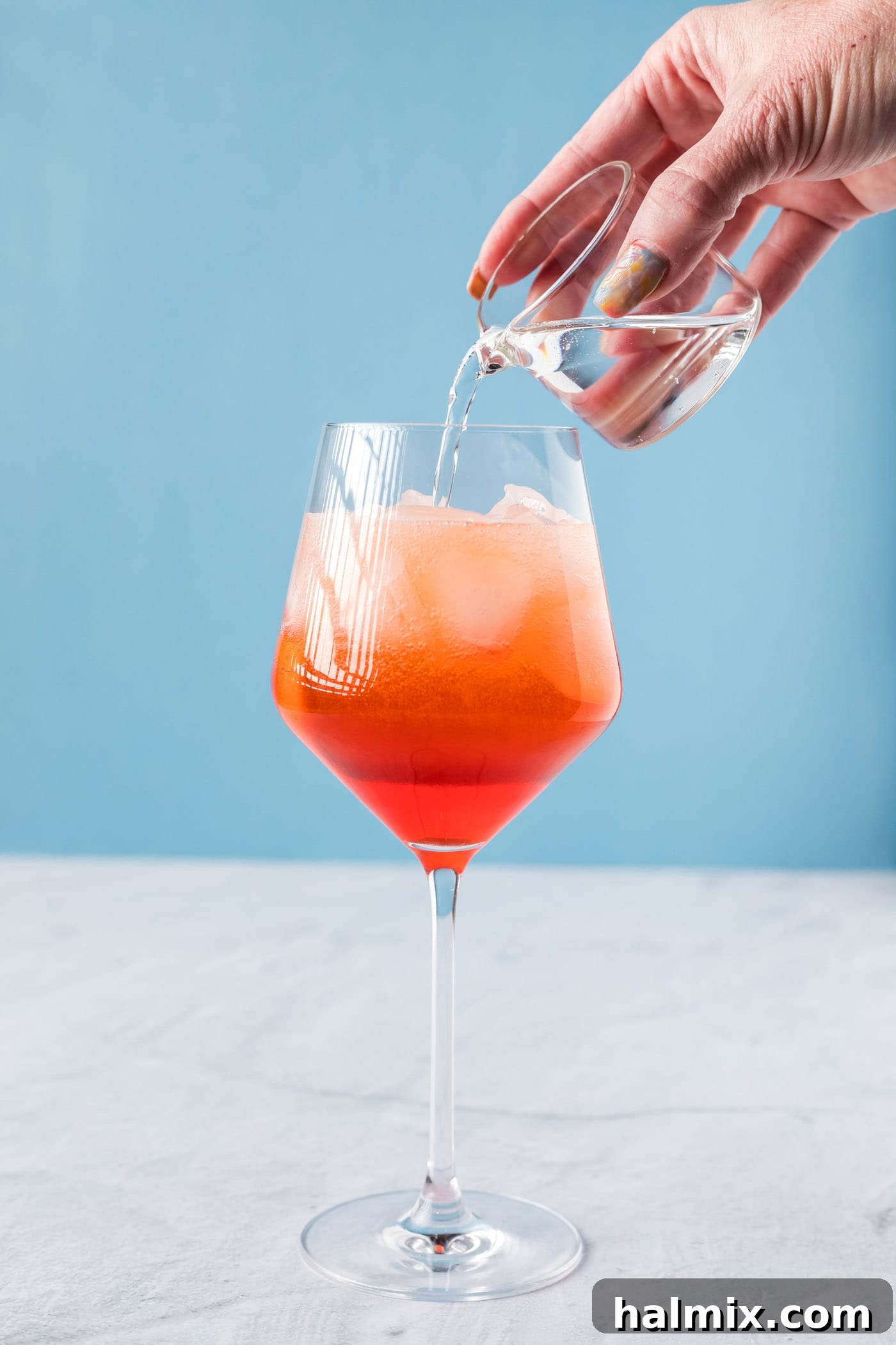 pouring club soda into aperol spritz