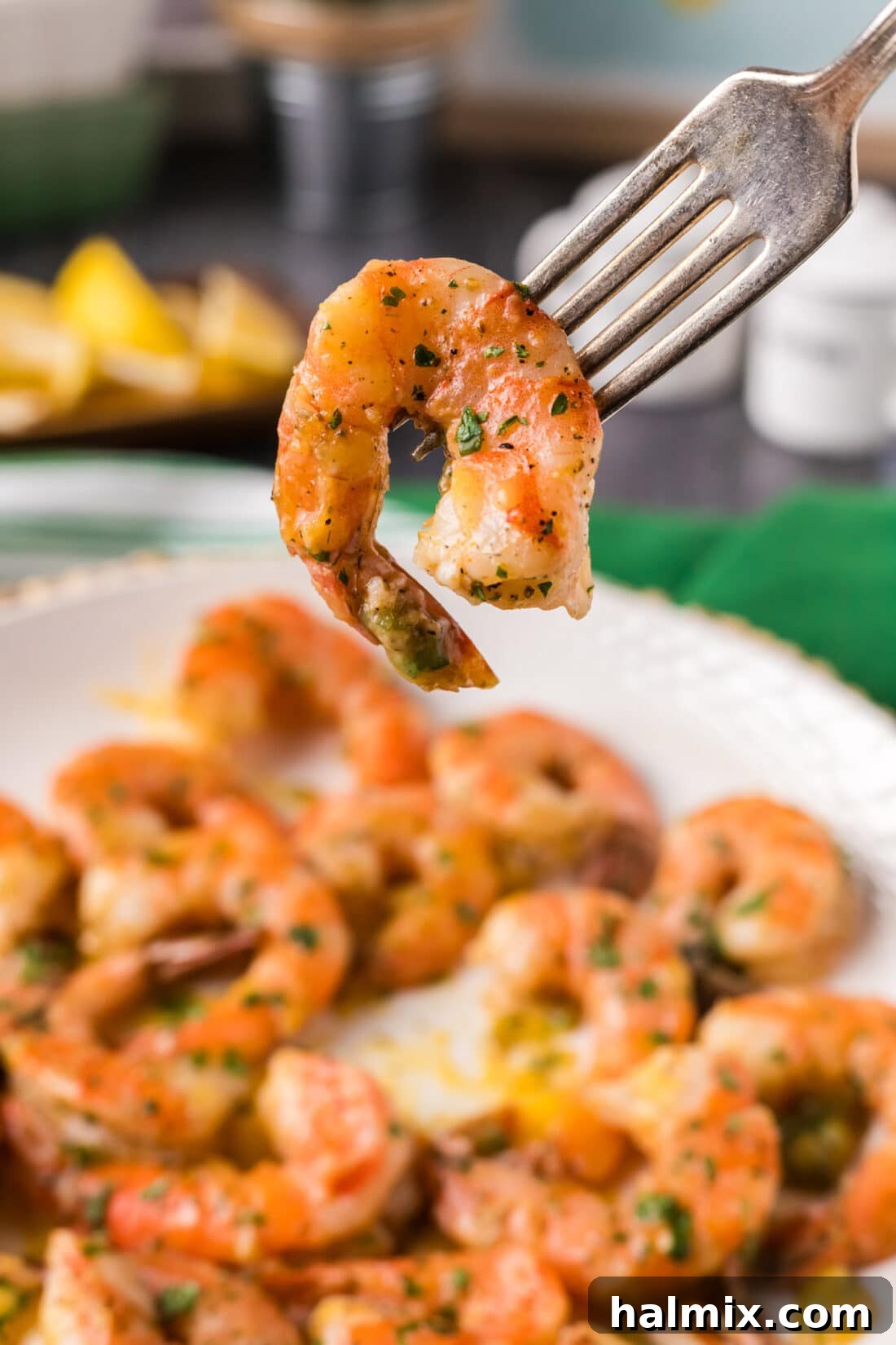 Garlic Butter Baked Shrimp 3 Close-up of a succulent baked shrimp held on a fork, highlighting its perfect cook and seasoning.