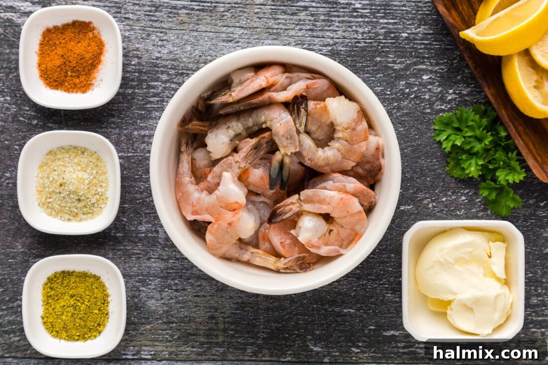 Garlic Butter Baked Shrimp 4 A flat lay photograph showcasing all the ingredients for baked shrimp: raw shrimp, melted butter, Old Bay, lemon pepper, and garlic salt.