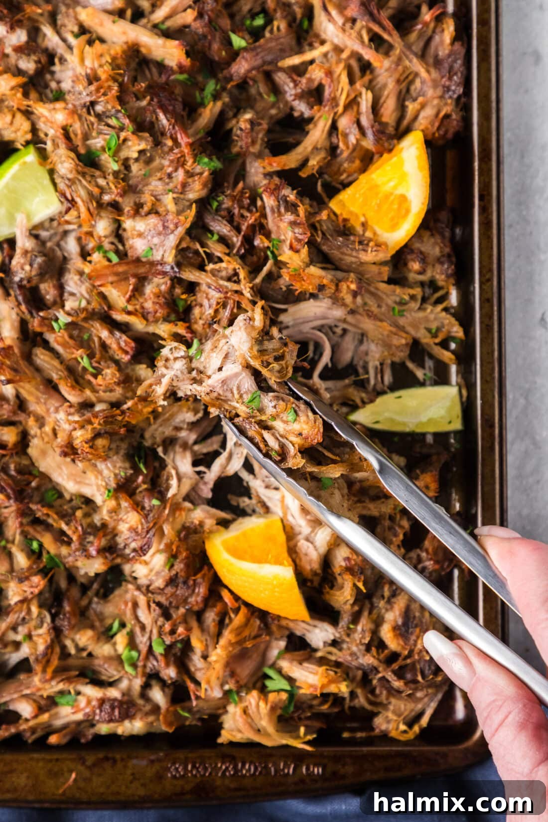 Crispy Instant Pot Carnitas 3 Tongs picking up Instant Pot Carnitas from a sheet pan