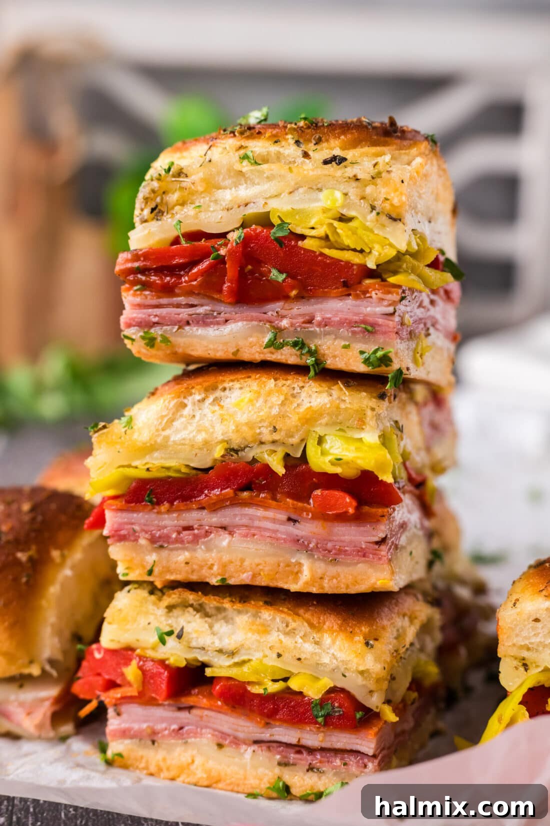 Stack of freshly baked Italian Sliders, golden brown and oozing with cheese and meats.