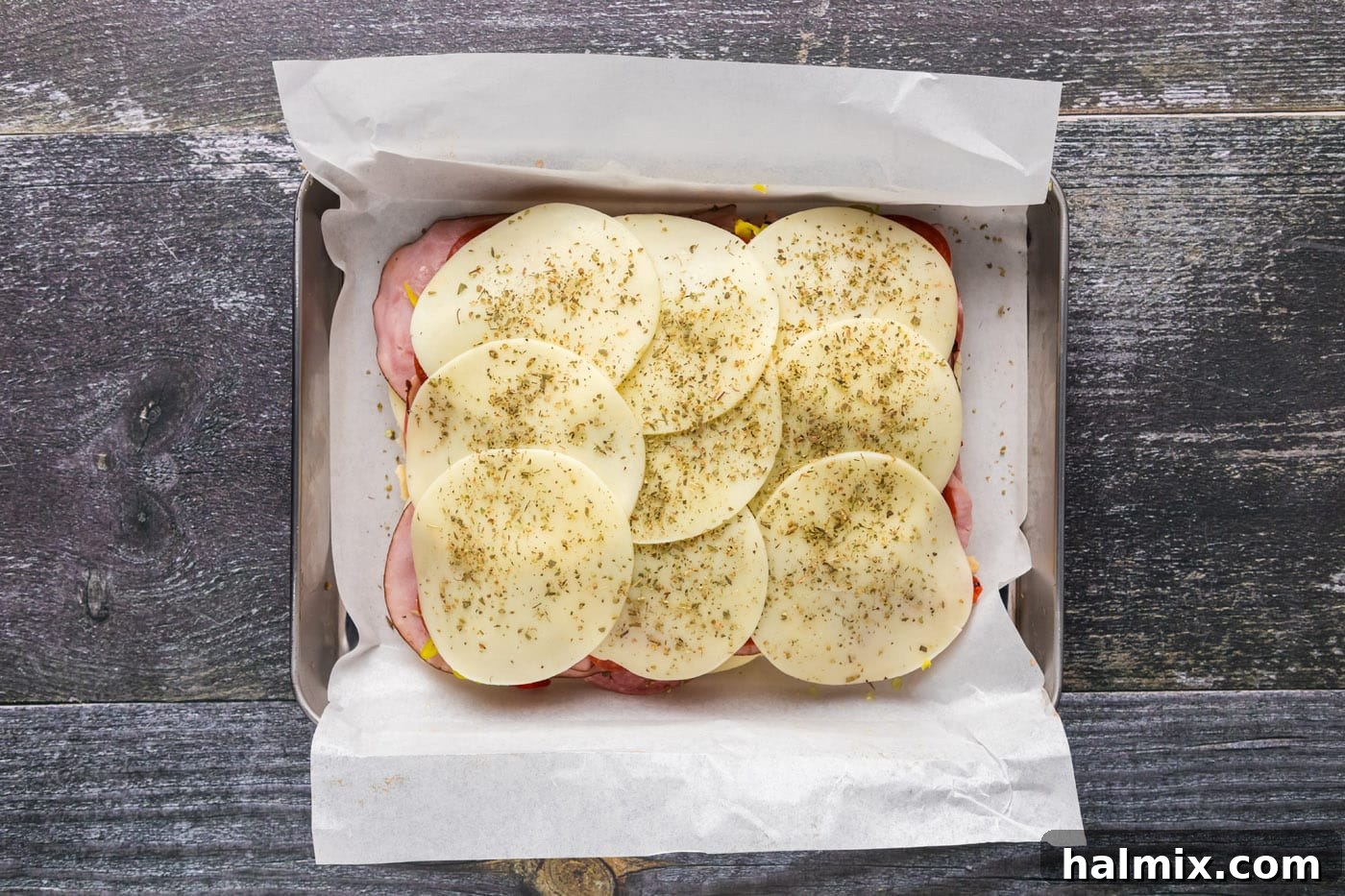 Final layer of provolone cheese on top of Italian sliders, ready for the top bun.