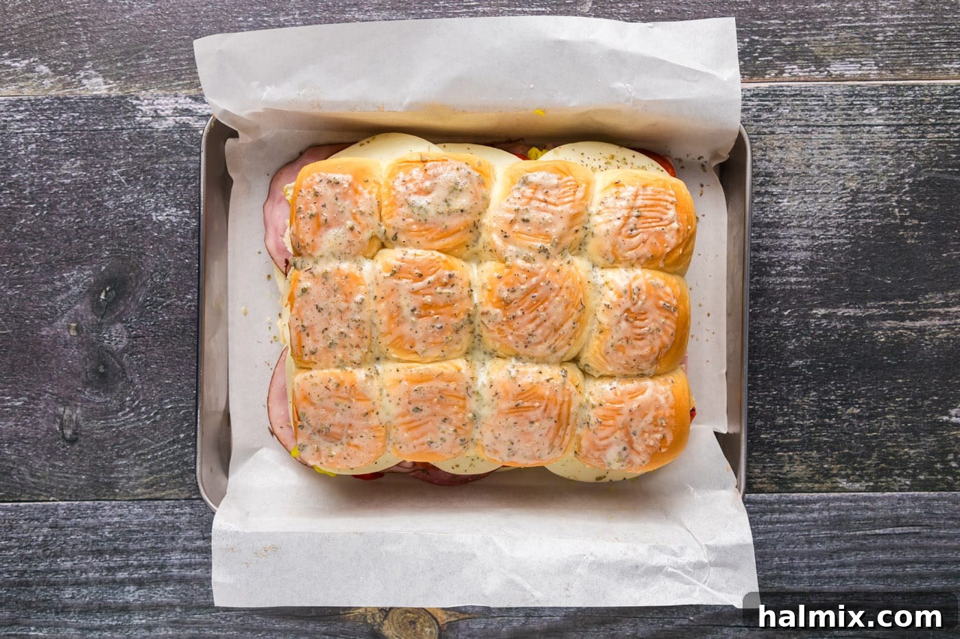 Assembled hot Italian sliders brushed with melted butter and seasoning.