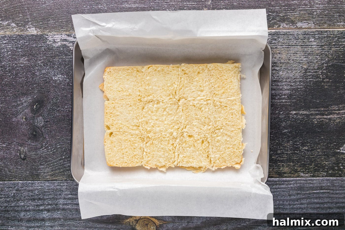 Bottom halves of slider buns placed in a parchment-lined baking sheet.