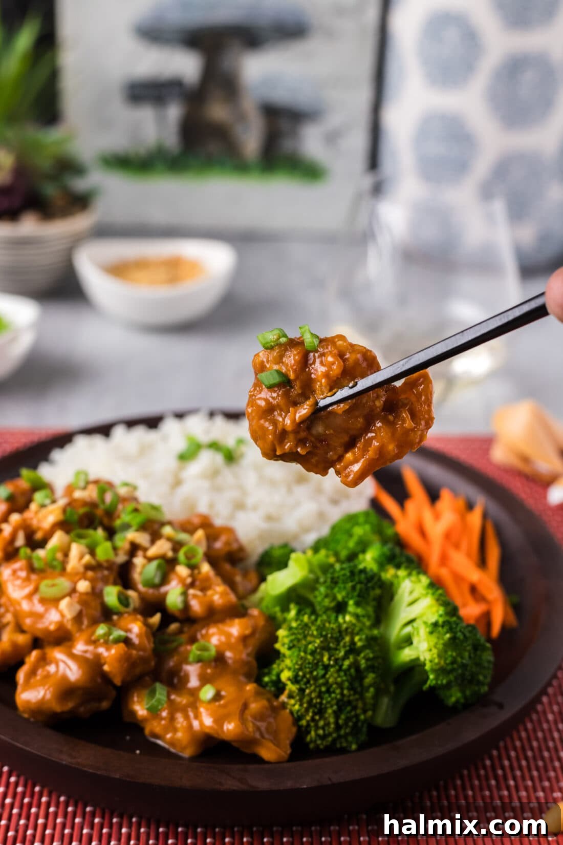 Chopsticks holding up a piece of Peanut Butter Chicken