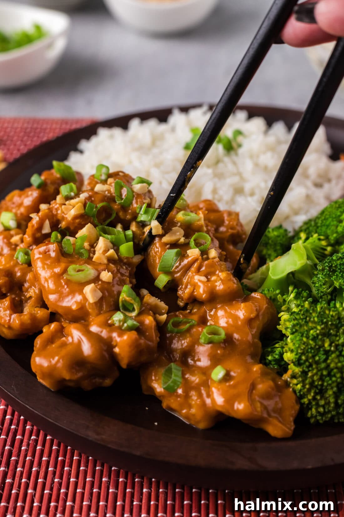 Chopsticks picking up a piece of Peanut Butter Chicken