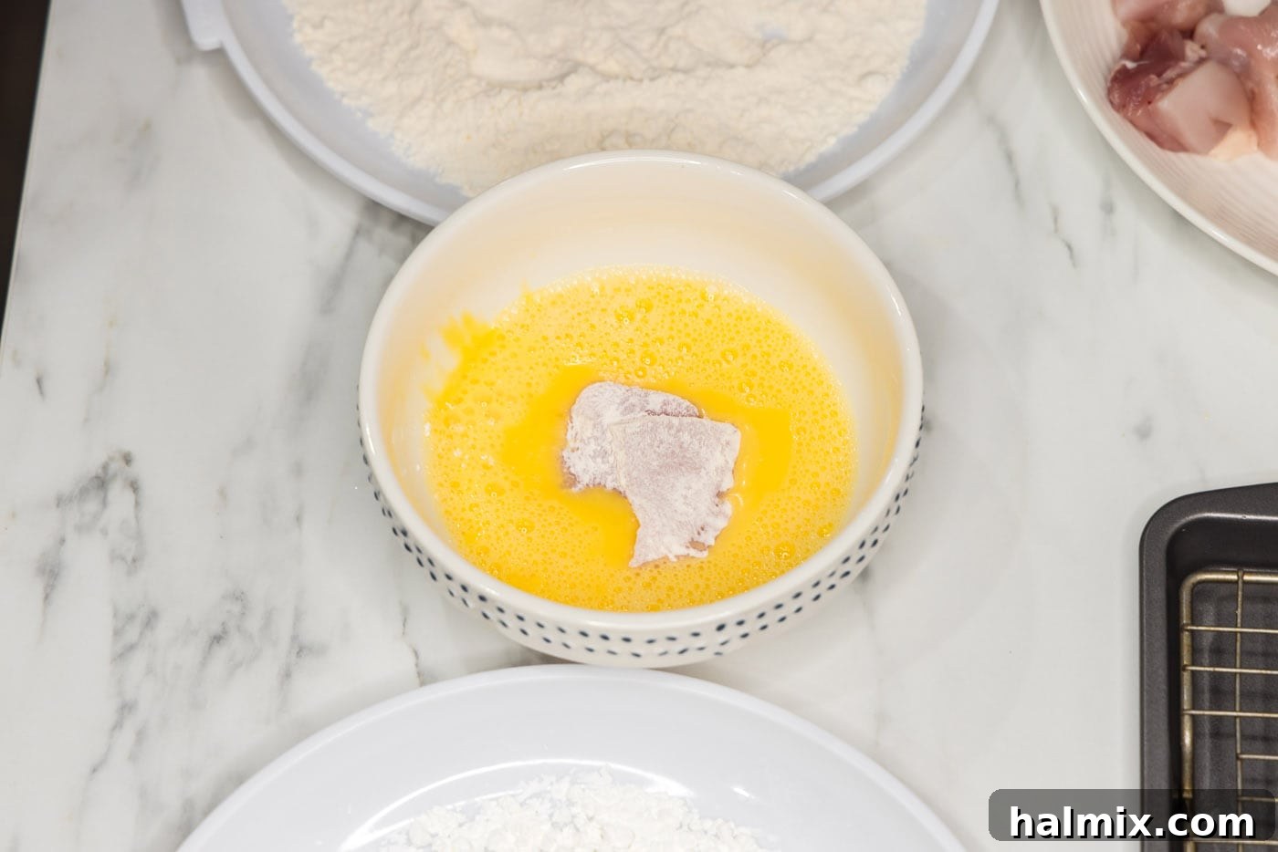 coating flour dredged chicken pieces in egg